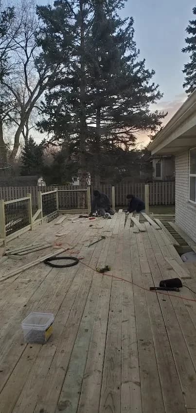 Two carpenters building a deck at dusk