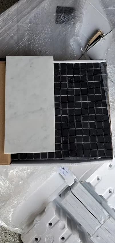Marble tile and black mosaic samples laid out for selection