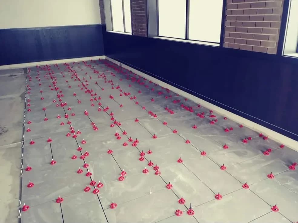 Large floor tiles set with red levelling clips