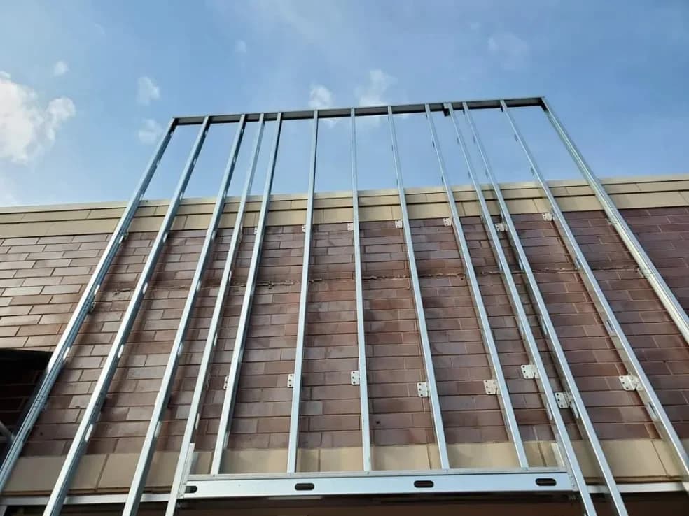 Metal stud framing going up against a brick wall