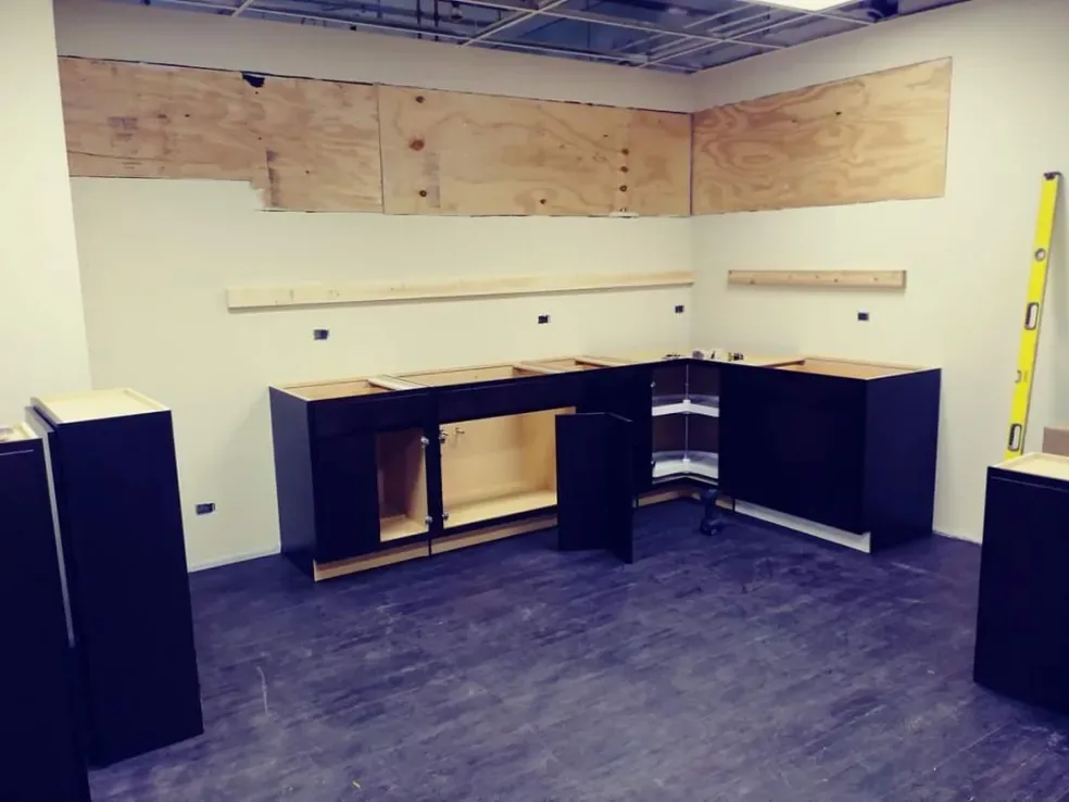 Base cabinets set in place against plywood backing